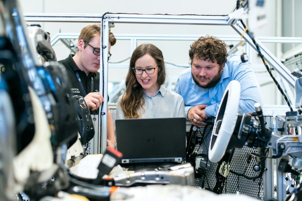 Tre persone esaminano un computer portatile accanto a un sistema di prova in laboratorio