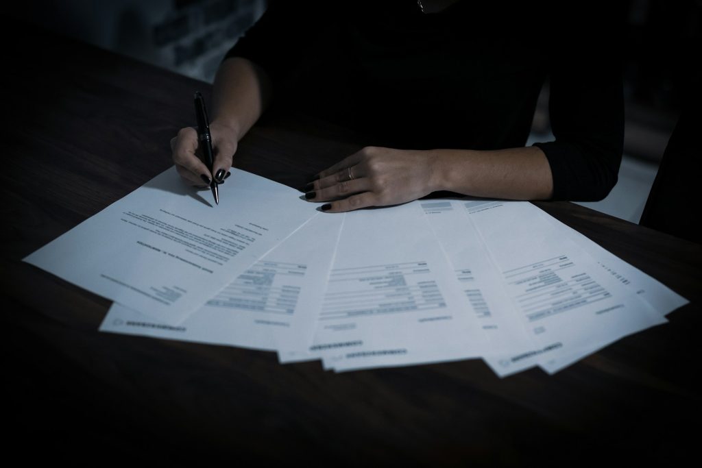 Persona che firma un documento con una penna, immagine illustrativa degli accordi di sublicenza