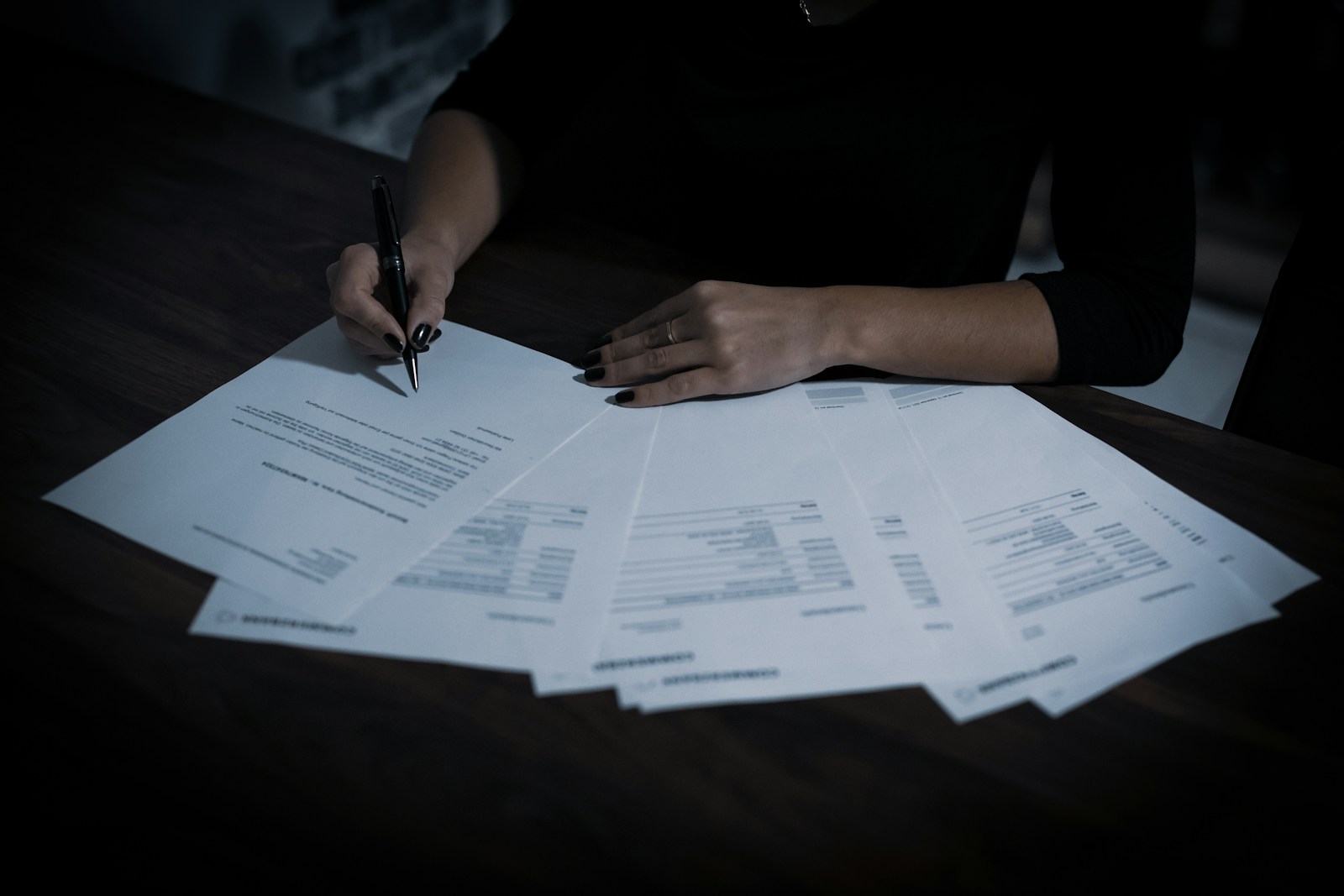 Persona che firma un documento con una penna, immagine illustrativa degli accordi di sublicenza