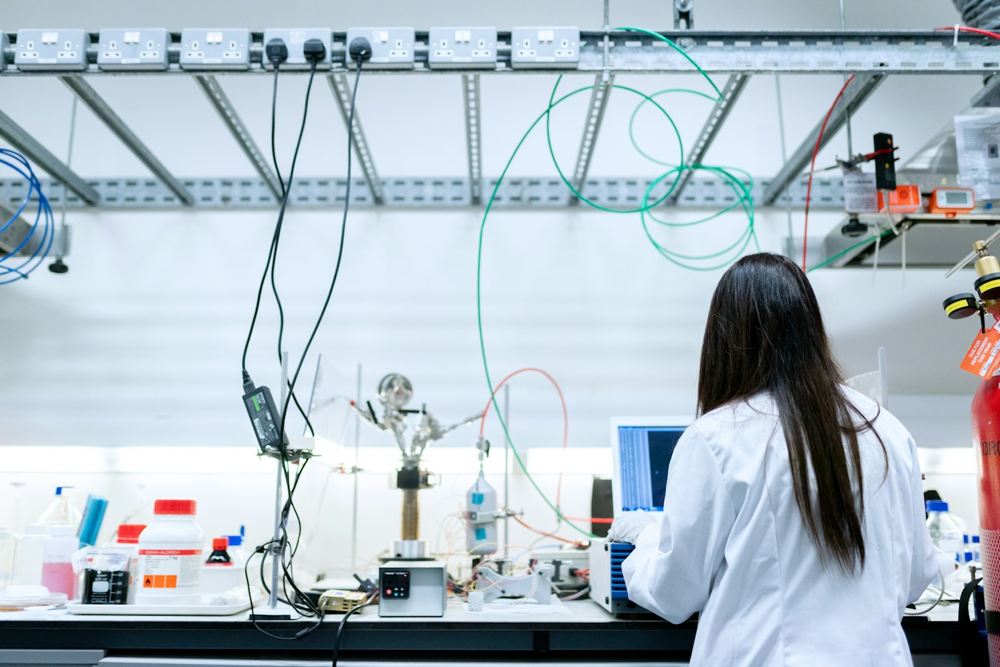 Ricercatrice al lavoro su un banco di laboratorio con apparecchiature sperimentali